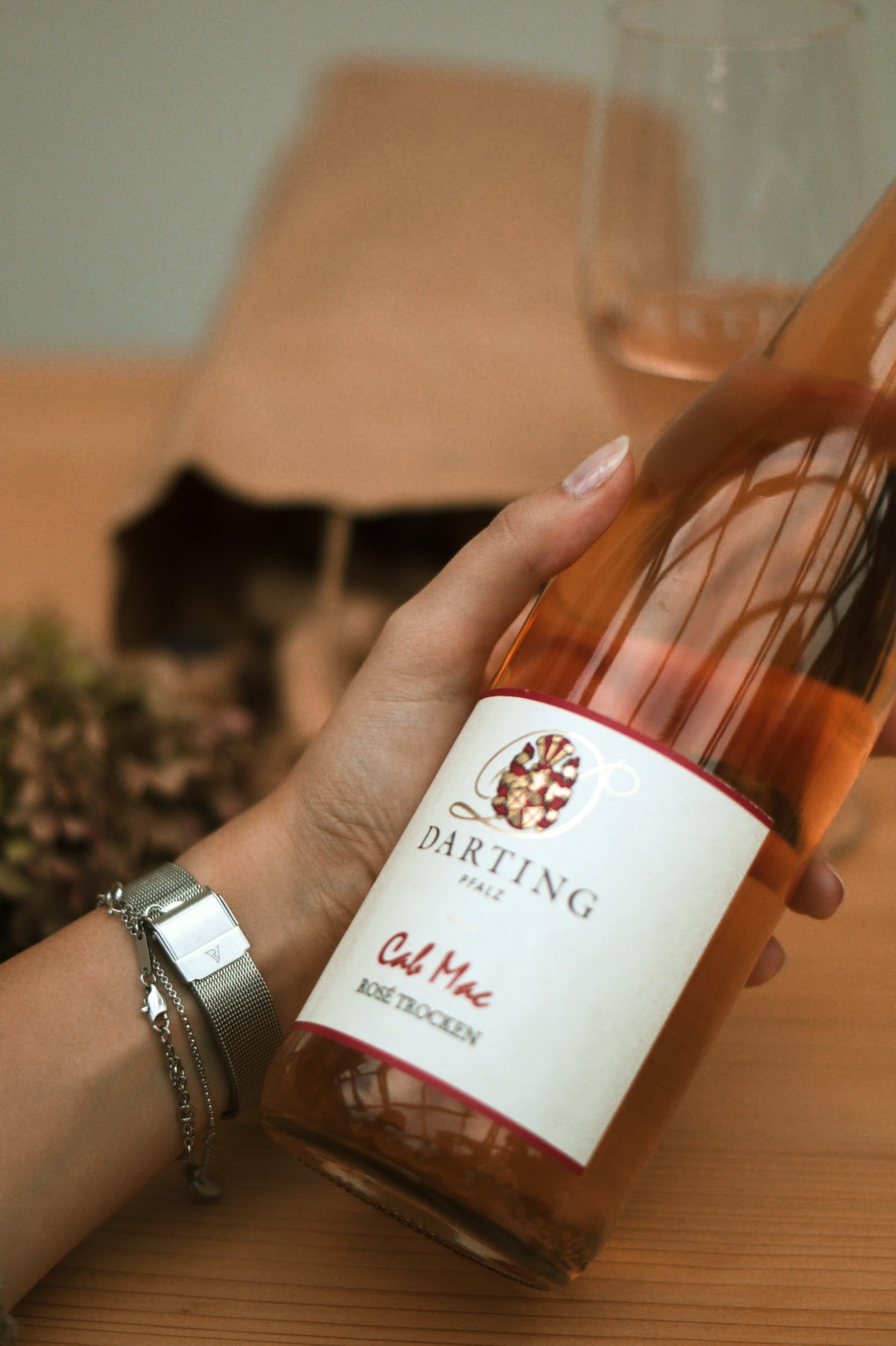 Eine Flasche Roséwein wird in der linken Hand leicht schräg gehalten. 